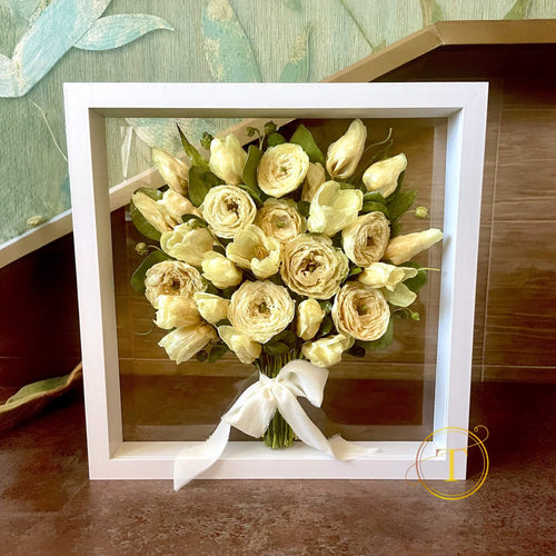 Framed bouquet of preserved flowers with a white ribbon with clear glass background