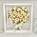 Preserved bouquet of wedding flowers in a white frame on a light gray background