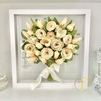 Preserved bouquet of wedding flowers in a white frame on a light gray background