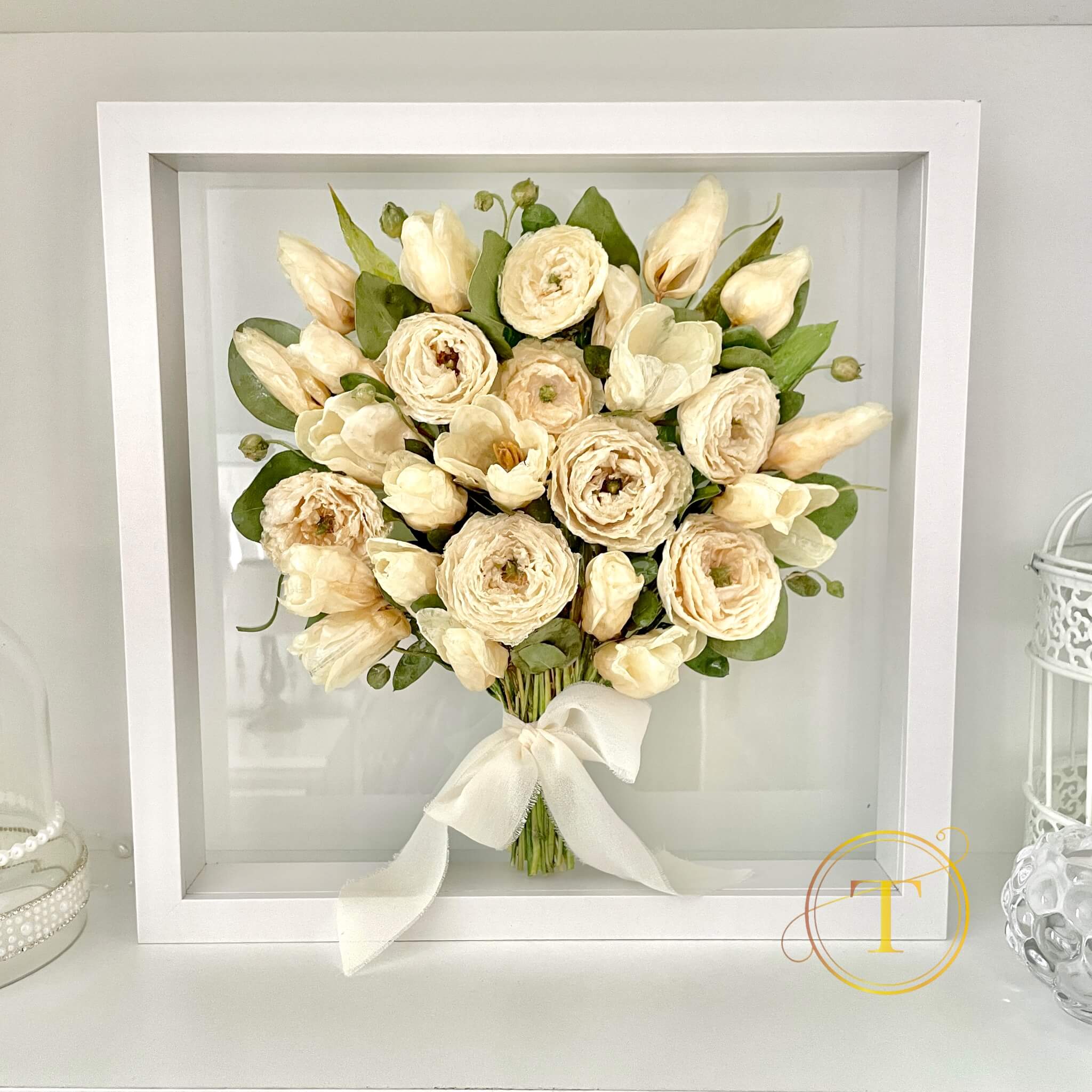 Preserved bouquet of wedding flowers in a white frame on a light gray background