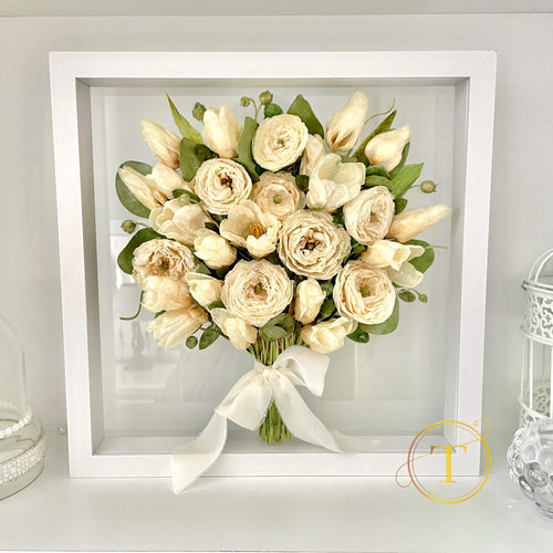 Preserved bouquet of wedding flowers in a white frame on a light gray background