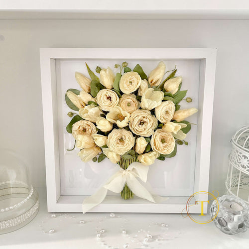 Framed bouquet of tulips and ranunculus on a white shelf