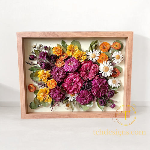Colorful floral arrangement in resin in a wooden frame on a cream background