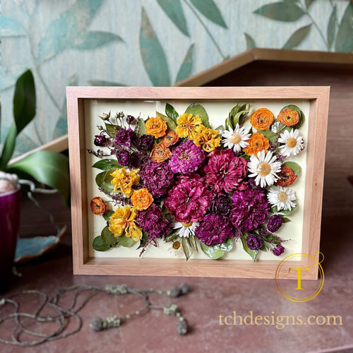 A framed arrangement of three-dimensional epoxy-coated flowers on a textured wooden frame.