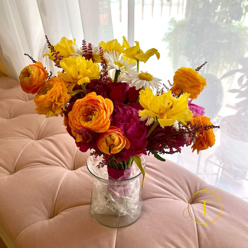 Wedding bouquet of colorful flowers in a clear vase on a pink cushion