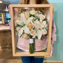 Buchet de mireasa cu crini albi conservat 3D in rasina, in rama natur, tinut in maini