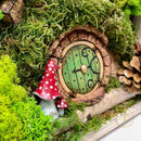 Detail view of handcrafted red toadstools adjacent to a charming Hobbit House 