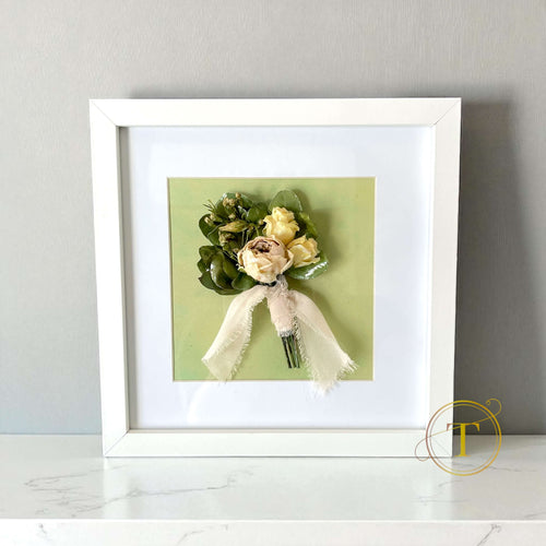 Framed boutonniere with flowers and ribbon on a light gray background