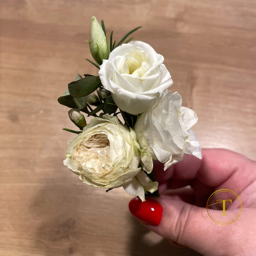 Hand holding a small bouquet of white flowers on a wooden surface