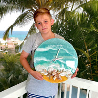 Three-dimensional blue-green wall clock in hands of a boy