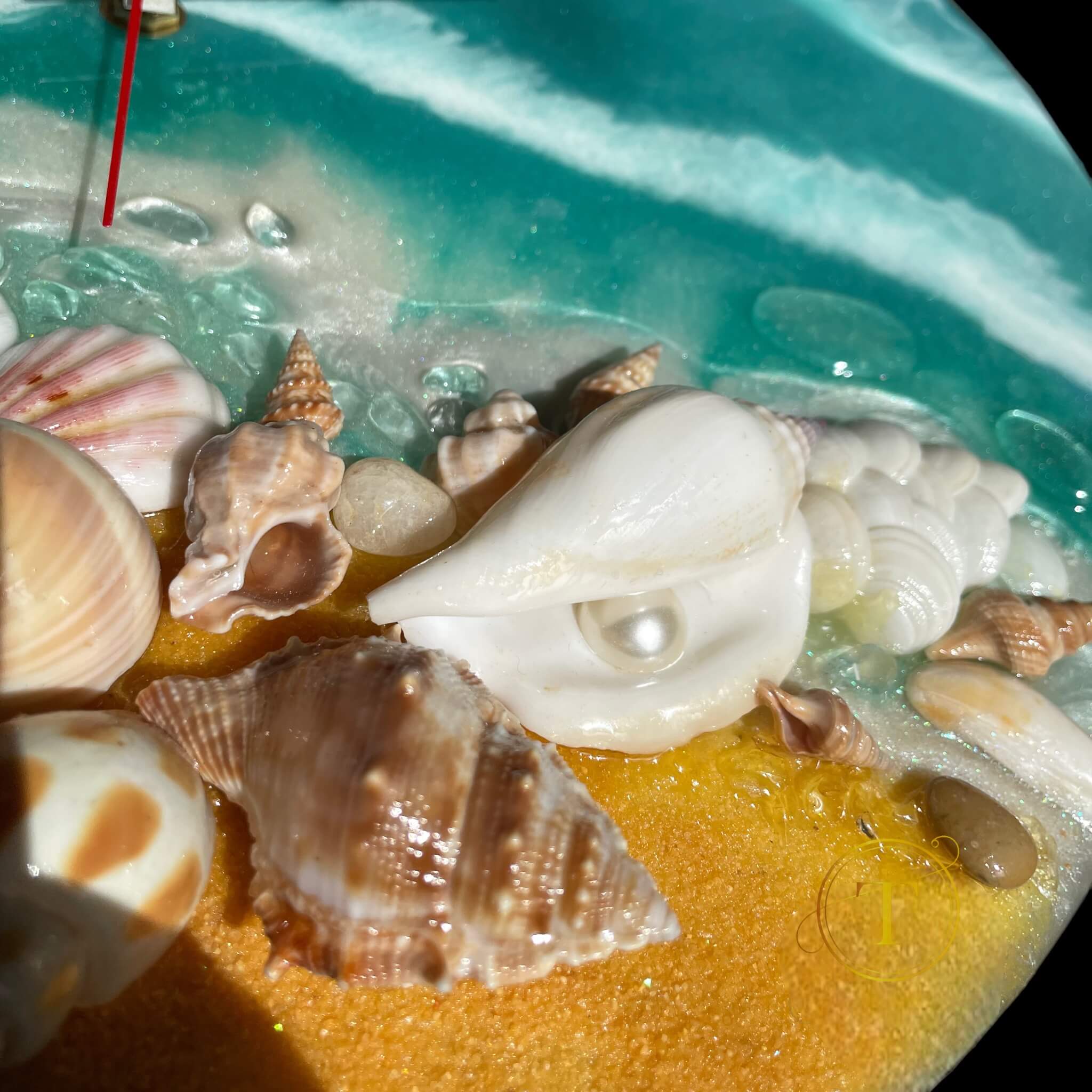 Close-up of seashore scene on epoxy resin wall clock with golden sand, shells and white pearl