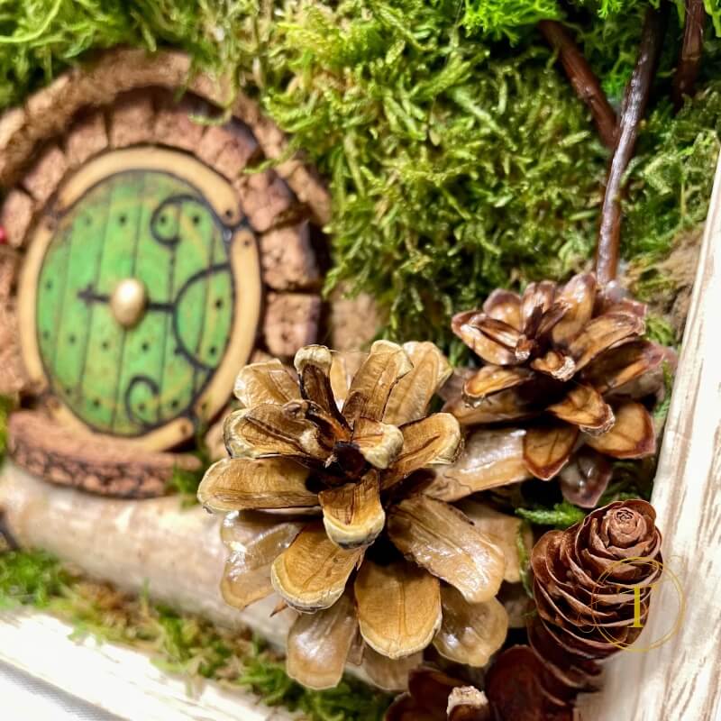 Close-up of pine cones, Hobbit door amid moss and lichen in a crafted landscape